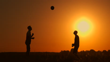 Zwei-Jungen-Spielen-Bei-Sonnenuntergang-Fußball.-Silhouette-Von-Kindern,-Die-Bei-Sonnenuntergang-Mit-Einem-Ball-Spielen.-Das-Konzept-Einer-Glücklichen-Familie.
